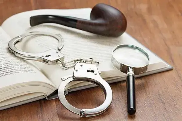 handcuffs and magnifying glass resting on open book