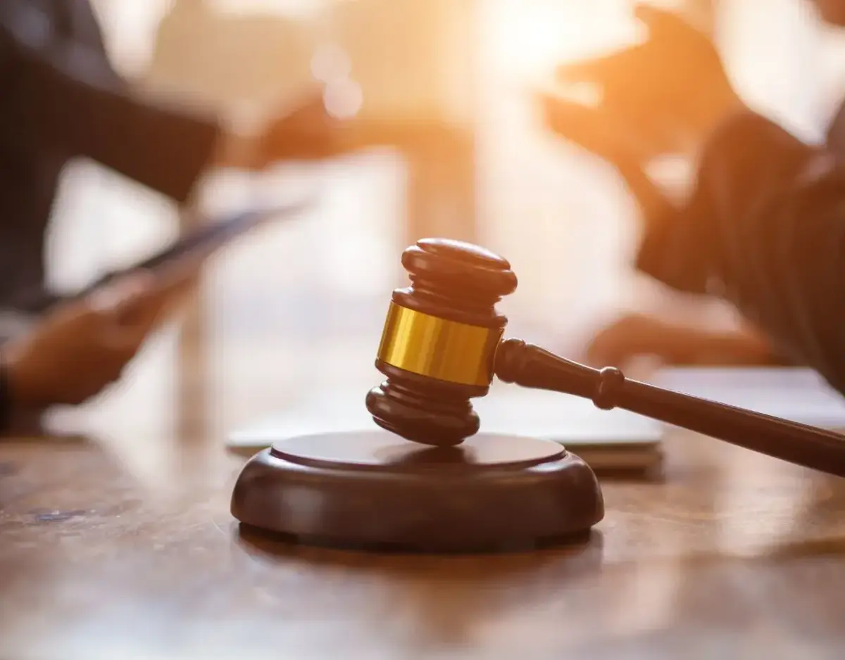 A gavel on a table with people in the background.