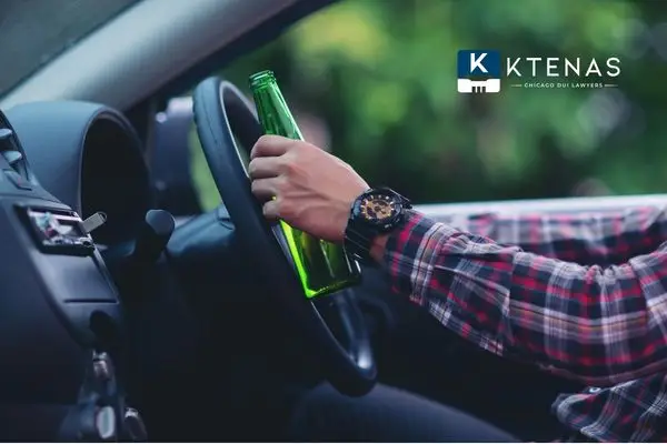 Person driving a car while holding a beer bottle.