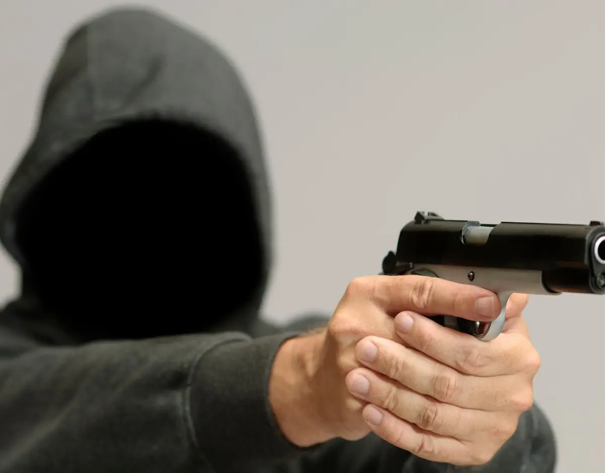man with hood hold a gun out