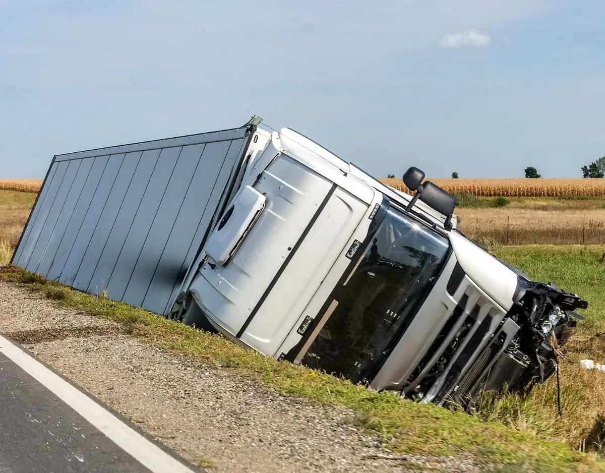 white truck tipped over on the side of the road
