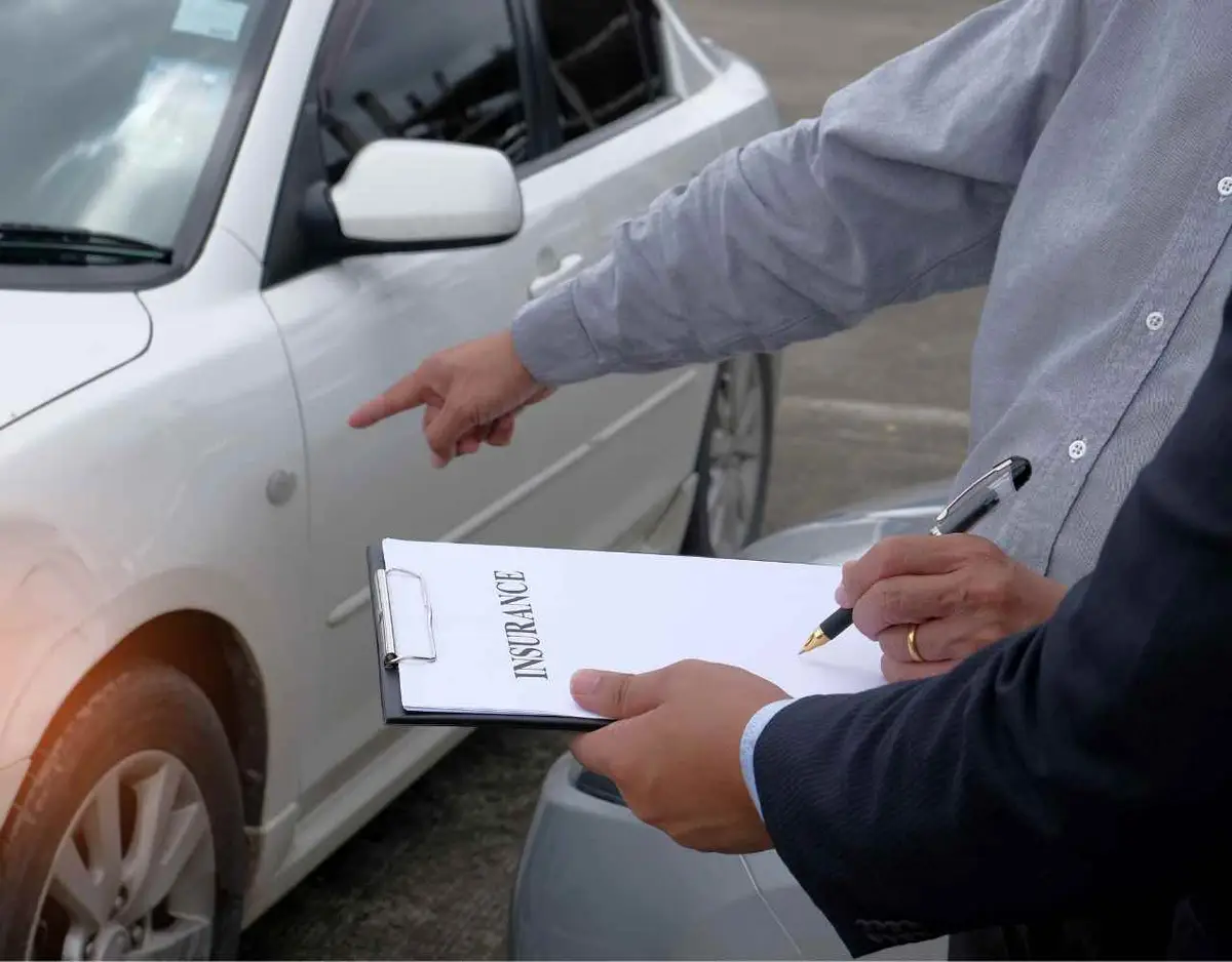 an insurance adjuster looking over a car involved in an accident claim