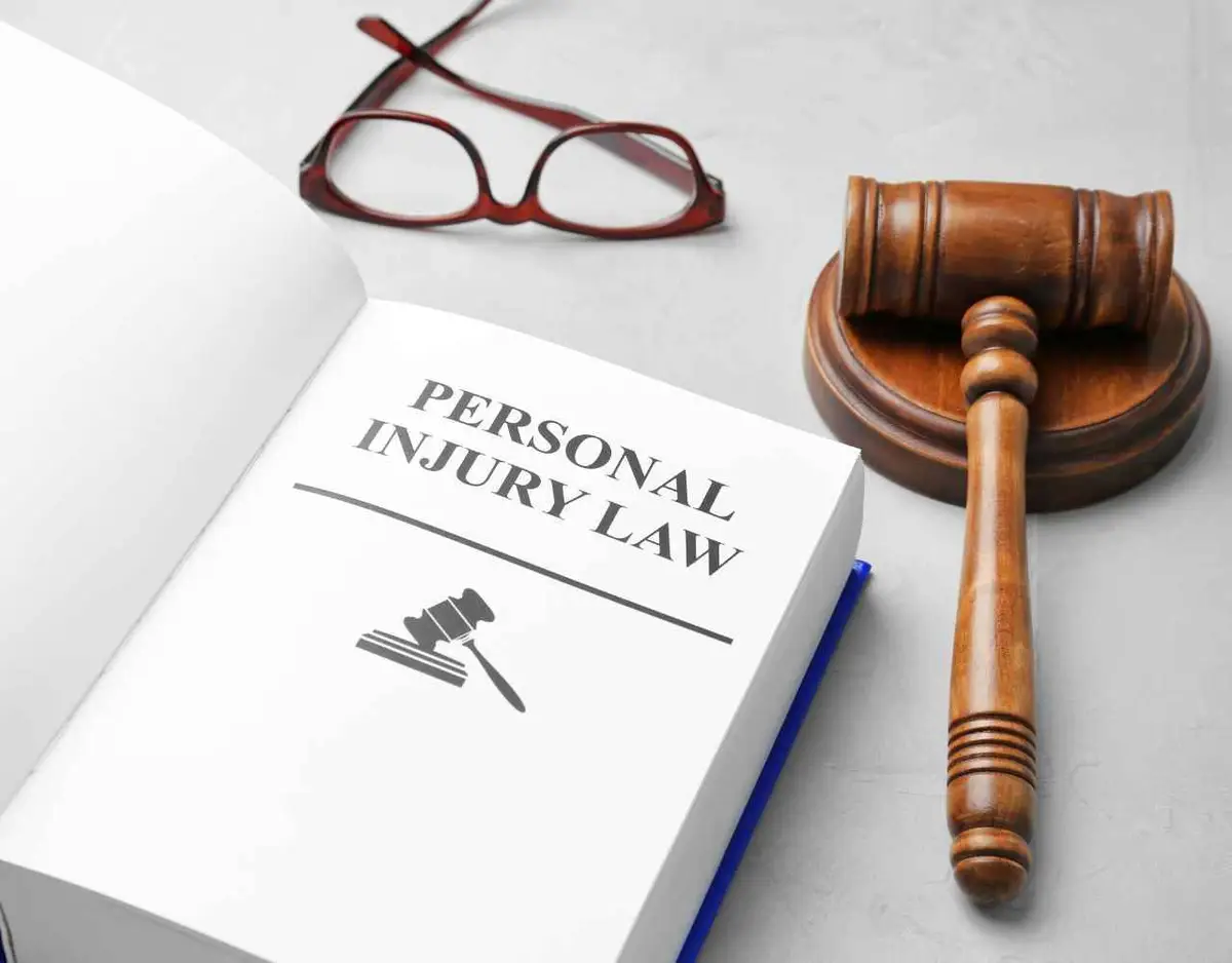 a law book covering personal injury statutes, glasses, and a gavel on a white desk