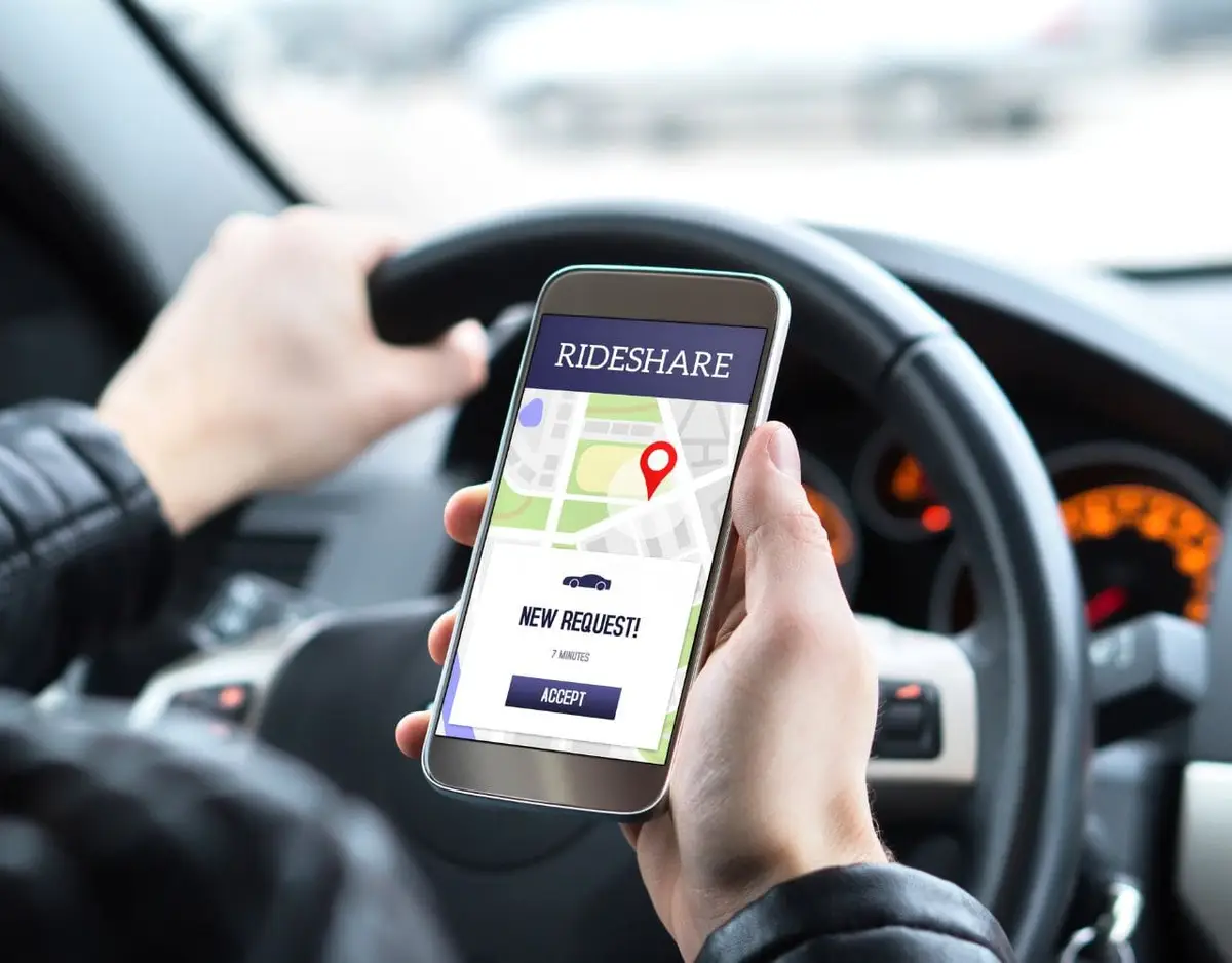 driver holding phone with rideshare app on screen
