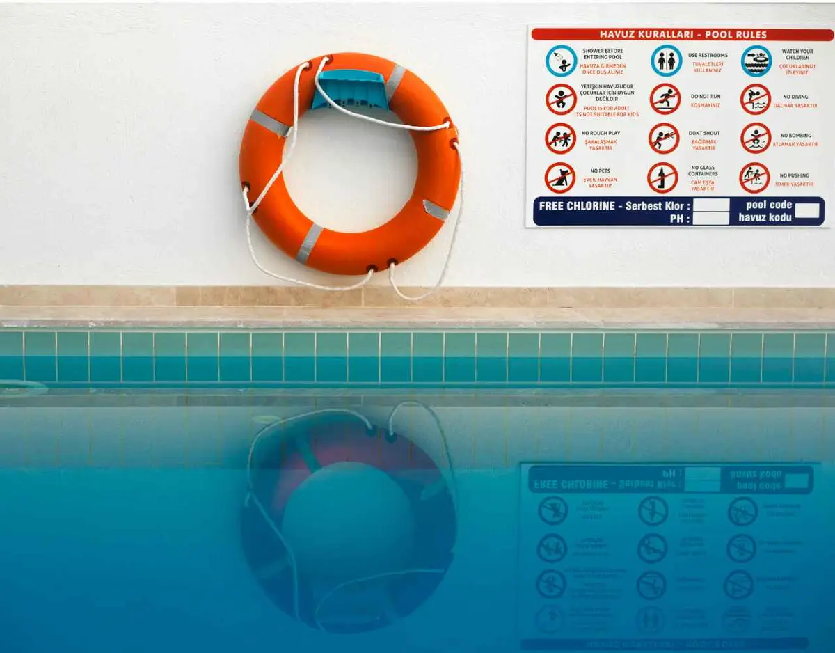 a floatation device and safety sign on a wall by a pool