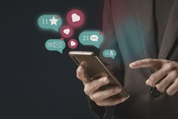 A person holding a phone with floating social media icons