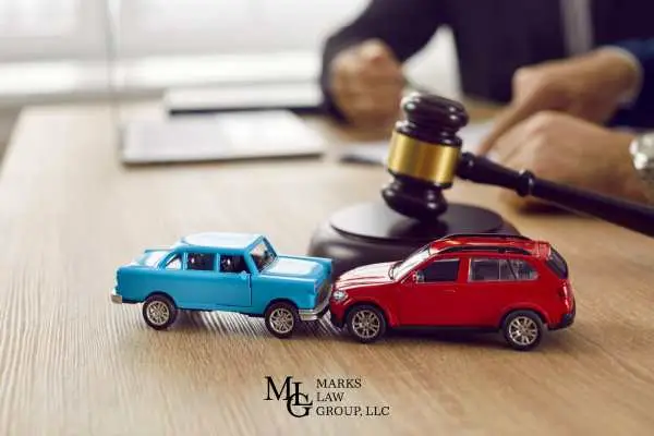 two model cars and a gavel on a desk while an attorney works on a lawsuit