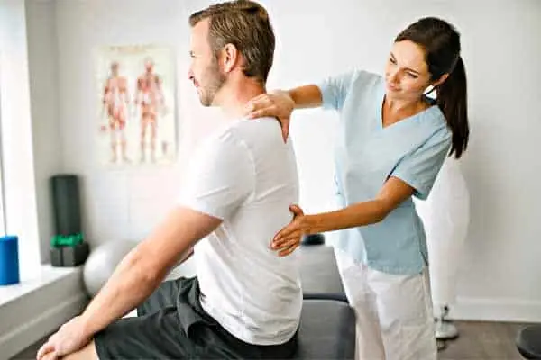 A physical therapist treating a male patient's back and neck.