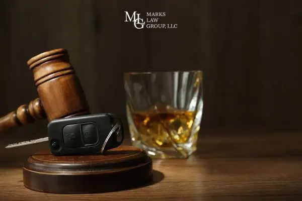 a gavel, glass of alcohol, and car key on a desk