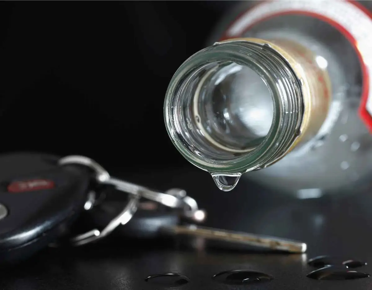 a car key and bottle of liquor in front of a black background