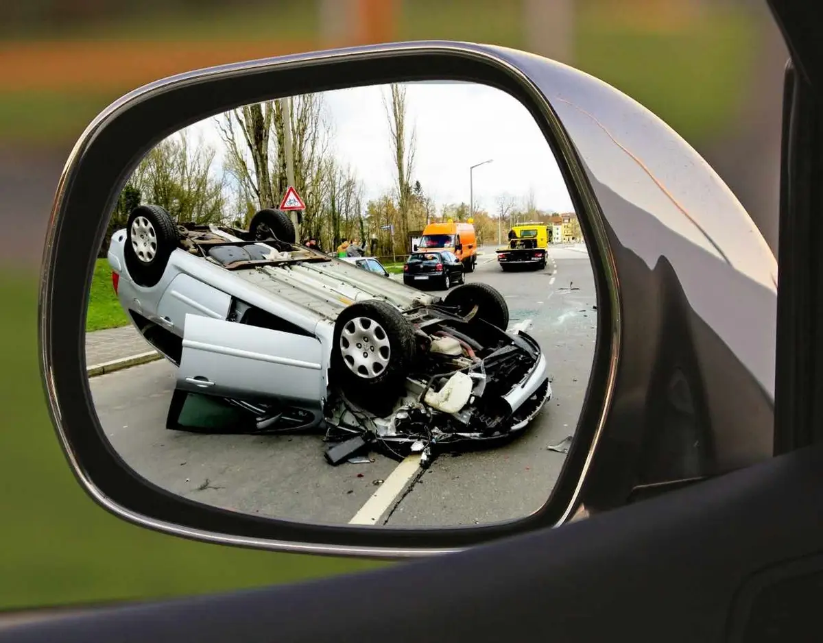 Overturned car wreck seen in a side-view mirror.