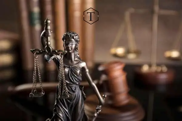 an attorneys desk with a gavel, legal books, and a statue on it