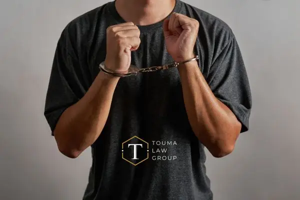 A man in a gray shirt with handcuffs on his wrists.