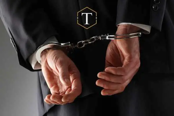 a man in a suit with his hands cuffed behind his back