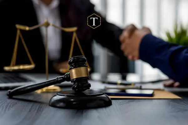 A judges gavel and two hands shaking in the background