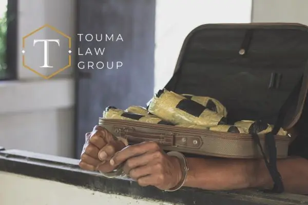 a person in handcuffs with a suitcase full of drugs