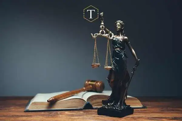 a desk with a legal book, gavel, and statue of justice on it