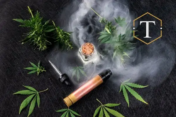 a THC vape on a table with some marijuana plants around it