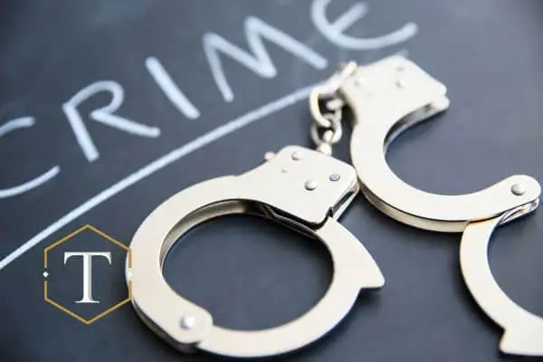 handcuffs on a chalkboard with the word "crime" written on it