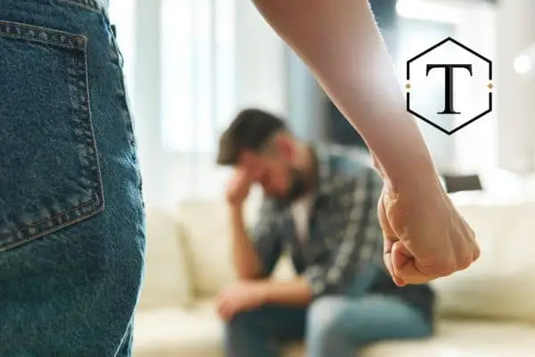 a man sitting on the couch with his partner balling her fist up