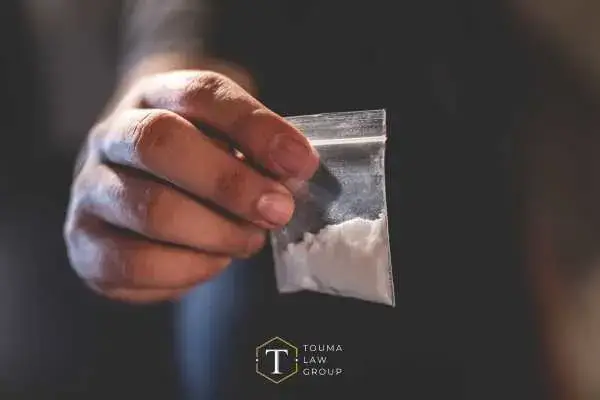 Zoomed in image of man holding small bag of cocaine