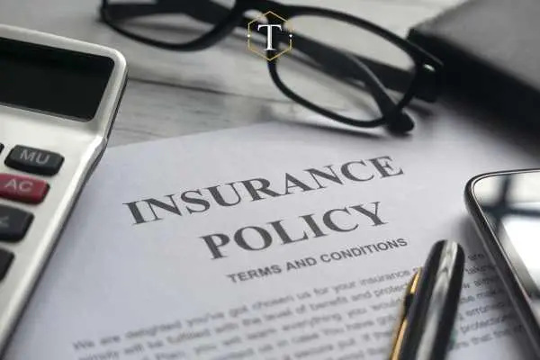 a car insurance form, pen, and glasses on a desk