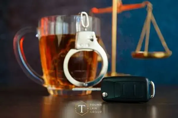 a beer, car key, gavel, and scales on a desk