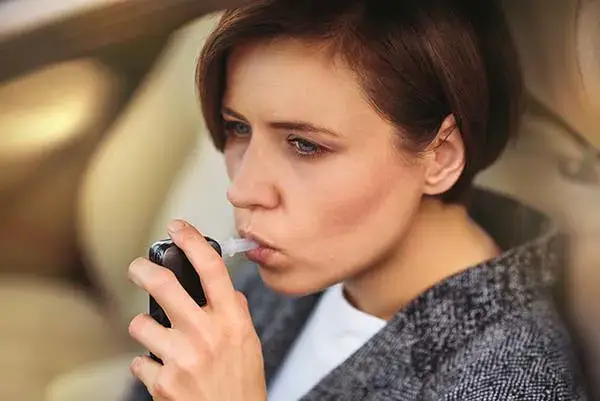 Woman taking breathalyzer test