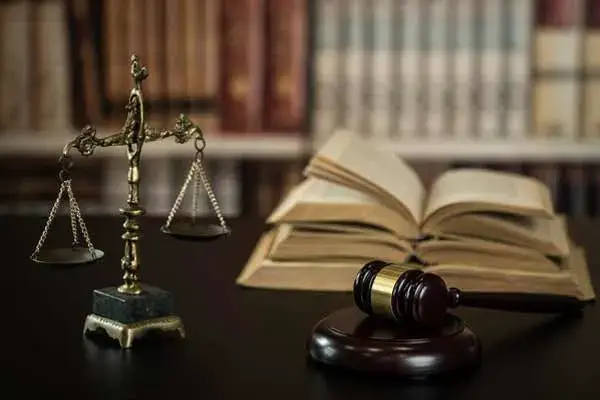A gavel, scale, and law books on a desk.