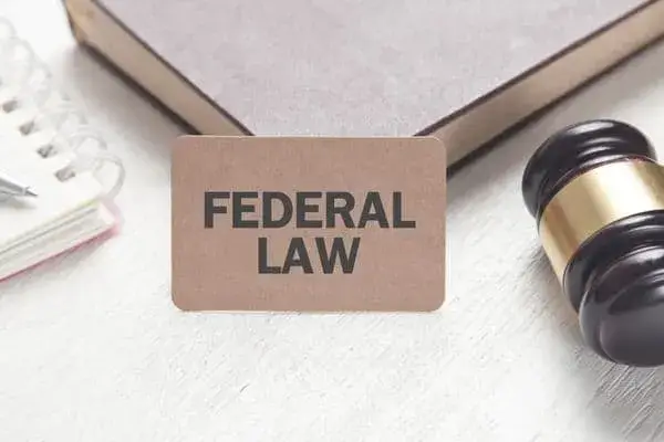 "federal law" on a desk with a gavel, book, and notepad.