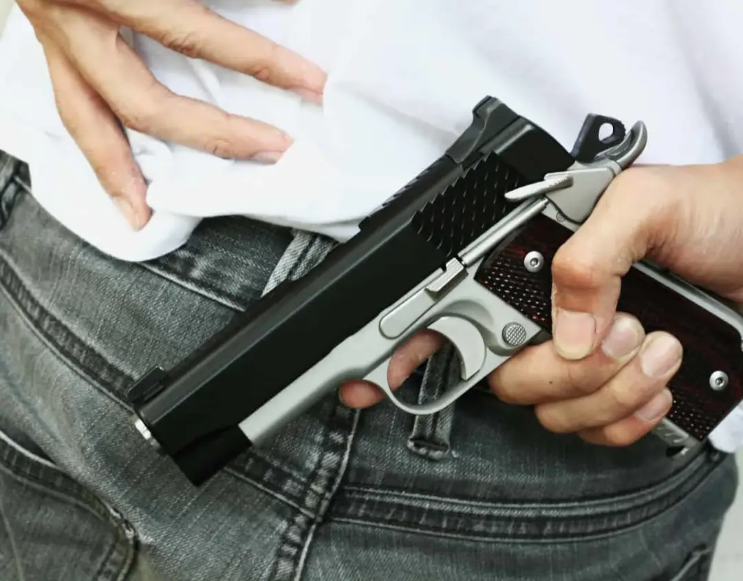 Man holding a black and silver gun behind back