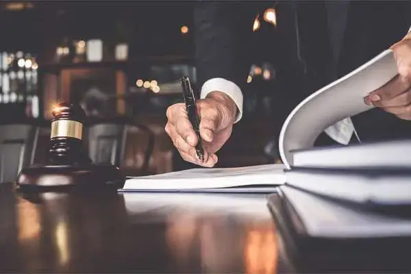 hombre firmando papeles al lado de un mazo