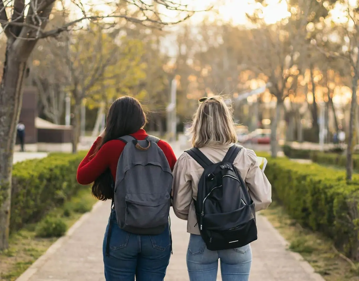 two college girls with backpacks walking on campus
