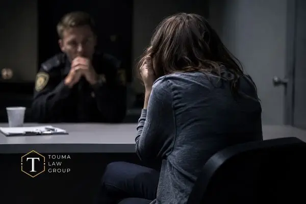 Woman sitting in an interrogation room with a police officer.